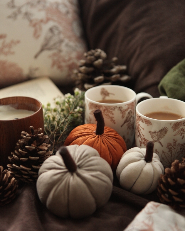 two mugs next to group of knitted pumpkins