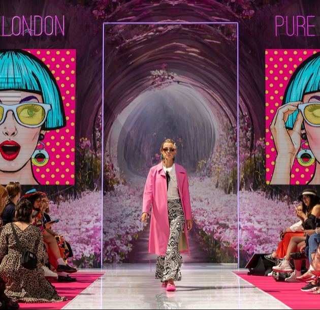 woman in a pink jacket walking down a runway