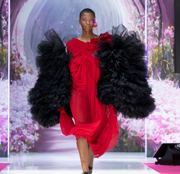 woman in a red dress walking down a runway